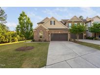 Charming home featuring brick accents, a two-car garage, and mature landscaping at 310 Alamosa Pl, Cary, NC 27519