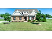 Charming home boasts a stone and siding facade, complemented by a lush green lawn and manicured landscaping at 3909 Mendenhall Dr, Zebulon, NC 27597