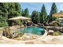 Stunning pool with a rock waterfall feature, surrounded by lush greenery and complete with lounge chairs for relaxation at 404 Brightling Way, Holly Springs, NC 27540