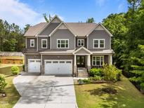 Inviting two-story home with a three-car garage, manicured lawn, and beautiful landscaping at 420 Creekhurst Pl, Cary, NC 27519