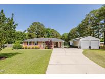 Charming one story brick house with mature landscaping and long driveway leading to a detached garage at 64 Red House Rd, Smithfield, NC 27577
