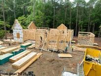 New home under construction with a wood frame and yellow dumpster in the foreground at 8021 Bud Morris Rd, Wake Forest, NC 27587