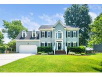 Charming two-story home featuring a manicured lawn, attached garage, and beautiful landscaping at 103 Chapelwood Way, Cary, NC 27518