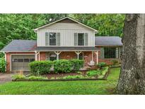 Charming two-story home featuring a brick exterior, green shutters, mature landscaping, and inviting front porch with swing at 1503 Laughridge Dr, Cary, NC 27511
