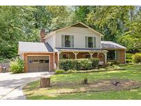 Charming two-story home with brick accents, lush landscaping, and an inviting front porch swing at 1503 Laughridge Dr, Cary, NC 27511
