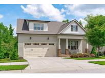 Charming home featuring a two-car garage, front porch with chairs, and beautiful landscaping at 2036 Amy Grace Ct, Fuquay Varina, NC 27526