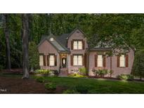 Charming brick home with brown shutters, lush landscaping, and a well-manicured lawn at 205 Benwell Ct, Cary, NC 27519