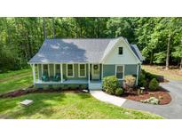 Charming home featuring a welcoming front porch, beautifully landscaped front yard, and a serene wooded backdrop at 2409 New Hope Church Rd, Chapel Hill, NC 27514