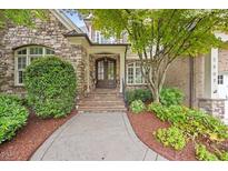 Stone-accented home featuring a stunning front entrance with a beautiful wooden door and lush landscaping at 2507 Mayview Rd, Raleigh, NC 27607