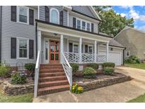 Inviting home featuring a charming front porch with brick steps and an orange front door at 2721 Dahlgreen Rd, Raleigh, NC 27615