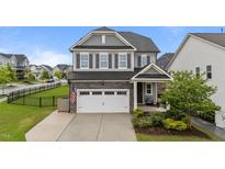 Charming two-story home featuring a gray exterior, a two-car garage, and manicured landscaping, with an American flag at 348 Golf Vista Trl, Holly Springs, NC 27540