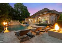 A luxury backyard features an in-ground pool, jacuzzi, sun loungers, and a fire pit, perfect for relaxing at night at 3829 Westbury Lake Dr, Raleigh, NC 27603