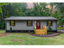 Charming single-story home with a gray exterior, a red front door, and a freshly stained natural wood porch and steps at 4420 W River Rd, Franklinton, NC 27525