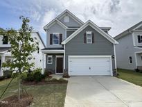 Charming two-story home with a two-car garage, manicured lawn, and professionally designed landscaping at 51 Commons Cir, Clayton, NC 27520