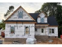 Under-construction home featuring black roof, white windows, and brick foundation on a partially cleared lot at 824 Emmett Ct, Spring Hope, NC 27882