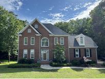 Beautiful two-story brick home with manicured lawn, mature trees, and inviting walkway to the front door at 1003 Wicksteed Ct, Apex, NC 27502