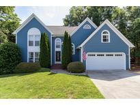 Charming blue two-story home featuring a well-manicured lawn, two-car garage, and inviting curb appeal at 103 Uxbridge Ct, Cary, NC 27513