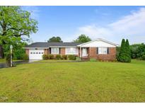 Charming brick ranch home with a well-maintained lawn and an attached two car garage at 1517 Hodges Chapel Rd, Benson, NC 27504