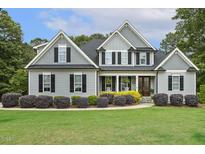 Charming two-story home featuring black shutters, gray siding, and a well-manicured front yard with lush landscaping at 205 Sherman Pines Dr, Fuquay Varina, NC 27526