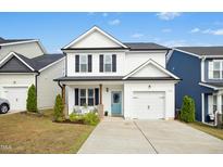Charming two-story home features a light blue front door, garage, and manicured lawn at 21 Diploma Dr, Clayton, NC 27520