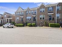 Charming brick townhomes with manicured landscaping and inviting front entrances along quiet street at 309 Old Mill Village Dr, Apex, NC 27502