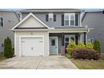 Charming two-story home with a white garage door, light green front door, and well-maintained landscaping at 34 Schoolhouse Way, Clayton, NC 27520
