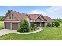 Charming home featuring a two-car garage, stone accents, and a beautifully landscaped front yard with lush green grass at 3465 Covington Trl, Mebane, NC 27302