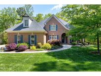 Charming brick home with manicured lawn, blue shutters, and lush landscaping at 404 Settlecroft Ln, Holly Springs, NC 27540