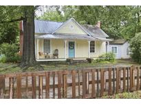 Charming yellow home with a cozy front porch featuring a swing and rocking chair and a brown wooden fence at 501 N Greensboro St, Carrboro, NC 27510