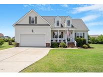 Charming home featuring a manicured lawn, a welcoming front porch, and an attached two-car garage at 518 Spruce Meadows Ln, Willow Springs, NC 27592