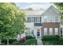 Charming townhome with a brick accent, flowering bushes and a well manicured lawn at 5742 Corbon Crest Ln, Raleigh, NC 27612