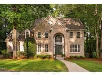 Charming brick home featuring a symmetrical facade, arched entryway and lush green lawn at 7808 Umstead Forest Dr, Raleigh, NC 27612