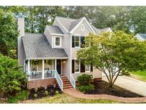 Charming two-story home with landscaped yard, a brick pathway, and a cozy front porch at 107 Ivy Hollow Ct, Morrisville, NC 27560