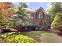 Beautiful brick home with lush landscaping and mature trees creating a serene outdoor space at 107 Silo Dr, Chapel Hill, NC 27514