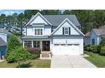 Charming two-story home with light blue siding, stone accents, an attached garage, and a well-manicured lawn at 1132 Heritage Knoll Dr, Wake Forest, NC 27587