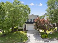 Charming two-story home with mature trees and a well-maintained lawn on a sunny, blue sky day at 12501 Garden Tree Ln, Raleigh, NC 27614
