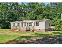 Charming home featuring a spacious wooden deck, neutral siding and neatly landscaped surroundings at 1392 L Cooper Rd, Cameron, NC 28326