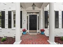Charming home featuring a black front door, white brick, shutters, brick walkway, and potted plants at 1404 Kings Lassiter Way, Raleigh, NC 27614