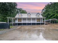 Charming home featuring a metal roof, covered porch, and large driveway perfect for country living at 1408 Old Ivey Rd, Apex, NC 27523