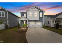 Charming two-story home featuring blue siding, white trim, a two-car garage, and manicured landscaping at 159 Wood Orchid Ln, Garner, NC 27529