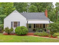 Charming home with landscaped front yard, awning covered porch, and red brick steps at 1915 James St, Durham, NC 27707