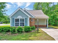 Charming single-story home featuring blue siding, brick accents, and a well-manicured lawn with green shrubs at 2 Donnelly Ct, Durham, NC 27713