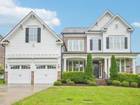 Stunning two-story home with a manicured lawn, white siding, stone accents, and a three-car garage at 203 S South Bend Dr, Durham, NC 27713