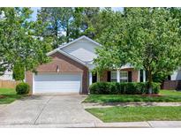 Charming single-Gathering home with brick and vinyl siding, lush greenery, and a two-car garage at 204 Southern Style Dr, Holly Springs, NC 27540