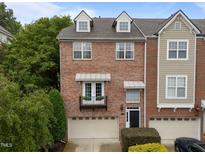 Charming brick townhome featuring a two-car garage, balcony, and dormer windows, offering a blend of classic and modern appeal at 2921 Imperial Oaks Dr, Raleigh, NC 27614