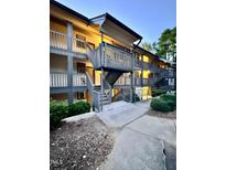 Condominium building with multiple stories, walkways, and stairs, surrounded by trees and landscaping at 3047 Huntleigh Dr, Raleigh, NC 27604