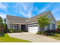 Charming home featuring blue siding, a two-car garage, manicured landscaping, and a well-maintained front yard at 3309 Turner Ridge Dr, New Hill, NC 27562