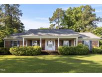 Charming brick home featuring a covered front porch with white columns and mature landscaping at 411 W Killiegrey St, Lillington, NC 27546