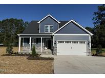 Charming two-story home showcasing blue siding, stone accents, and a two-car garage under a clear blue sky at 4167 Old Stage N Rd # 4, Angier, NC 27501