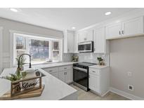 Bright kitchen features white cabinets, quartz countertops, stainless steel appliances, and a large bay window at 4307 Pope Rd, Durham, NC 27707